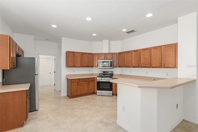 kitchen featuring kitchen peninsula, appliances with stainless steel finishes, and a textured ceiling