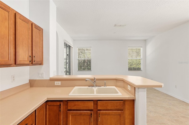 kitchen featuring a textured ceiling, kitchen peninsula, and sink