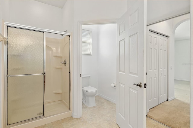 bathroom featuring toilet and a shower with shower door