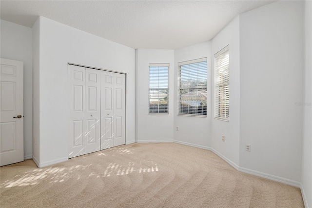 unfurnished bedroom featuring light carpet, a closet, and a textured ceiling