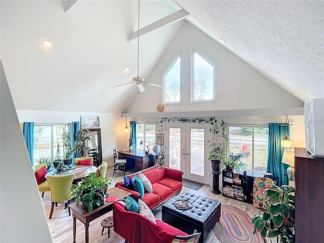 living room with a wealth of natural light, light hardwood / wood-style flooring, ceiling fan, and french doors