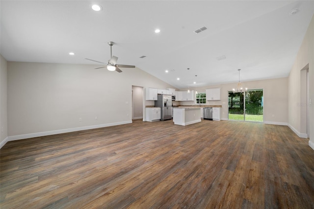 unfurnished living room with dark hardwood / wood-style flooring, ceiling fan with notable chandelier, and vaulted ceiling