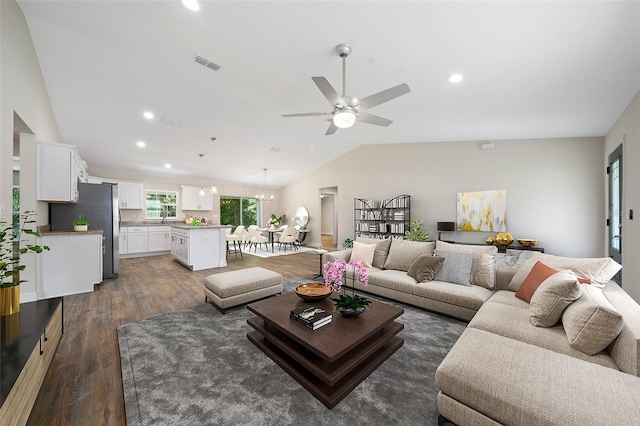 living room featuring ceiling fan with notable chandelier, dark hardwood / wood-style flooring, vaulted ceiling, and sink