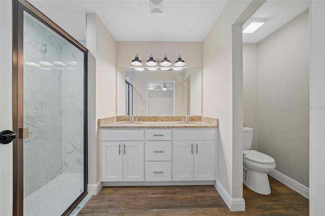 bathroom with hardwood / wood-style floors, vanity, toilet, and a shower with shower door