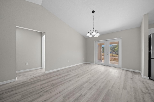 unfurnished dining area featuring a chandelier, lofted ceiling, french doors, and light hardwood / wood-style flooring