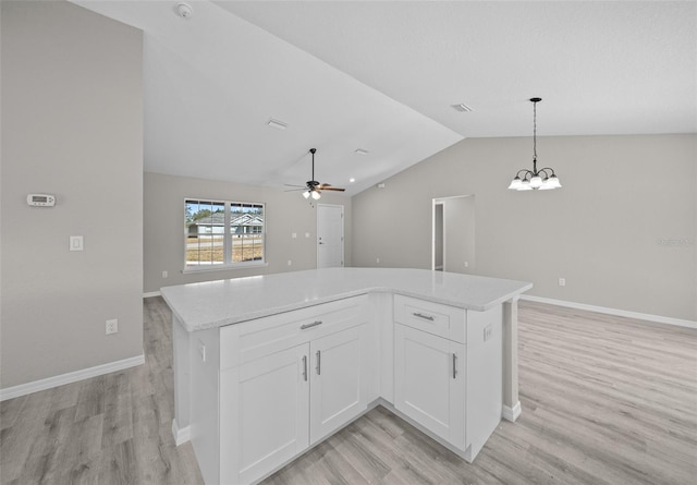 kitchen featuring ceiling fan with notable chandelier, light hardwood / wood-style flooring, white cabinetry, hanging light fixtures, and lofted ceiling