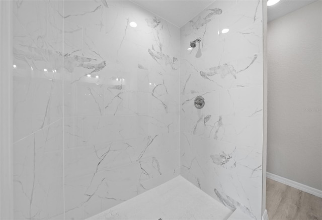 bathroom with tiled shower and hardwood / wood-style floors