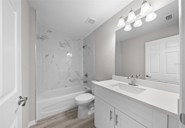 full bathroom with vanity, tiled shower / bath, toilet, a textured ceiling, and wood-type flooring