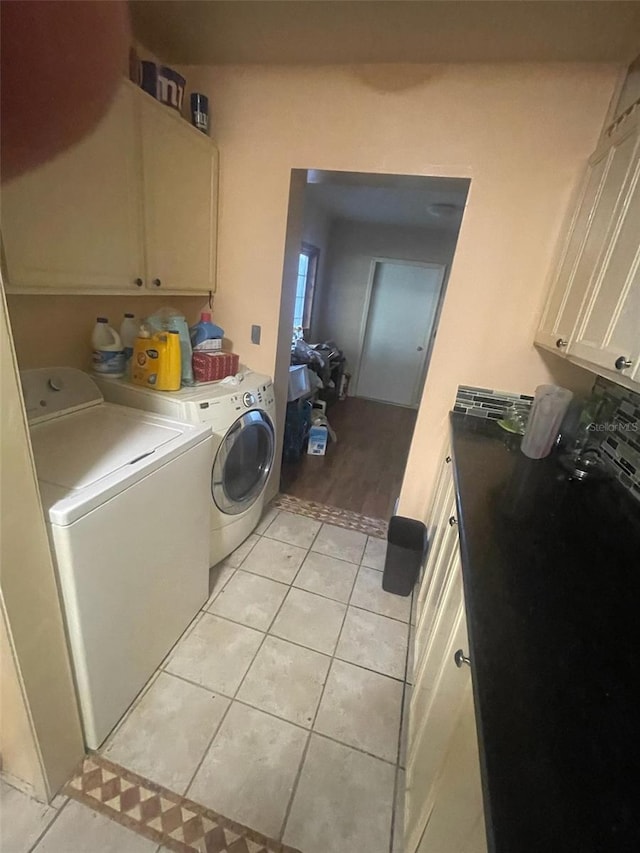 laundry room with washer and dryer, cabinets, and light tile patterned floors