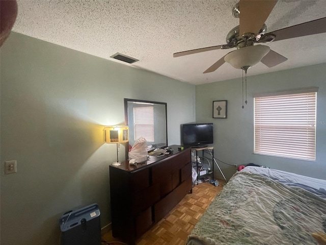 bedroom featuring ceiling fan, light parquet flooring, and a textured ceiling