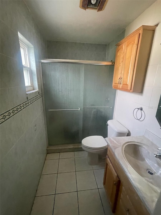 bathroom featuring vanity, tile patterned flooring, toilet, tile walls, and walk in shower