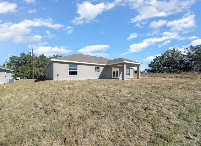 back of property featuring central AC unit and a yard