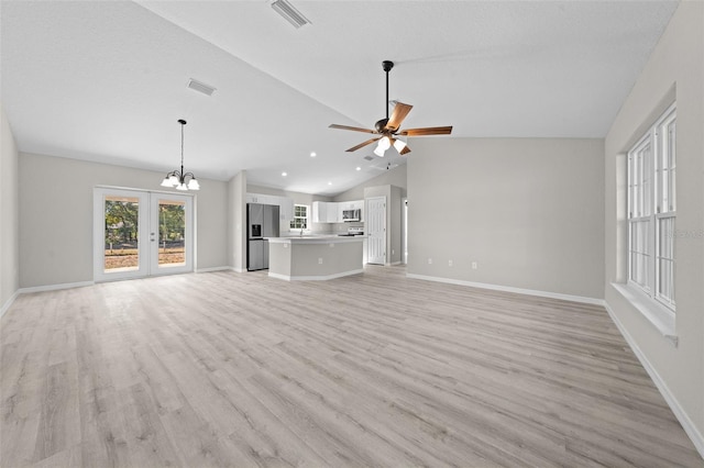 unfurnished living room featuring ceiling fan with notable chandelier, light hardwood / wood-style floors, lofted ceiling, and french doors