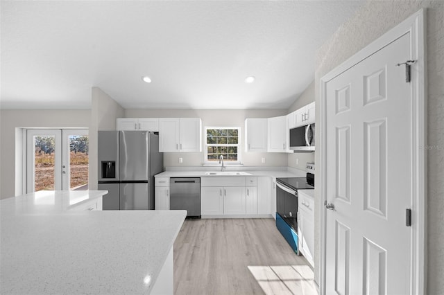 kitchen with white cabinets, appliances with stainless steel finishes, a healthy amount of sunlight, and sink