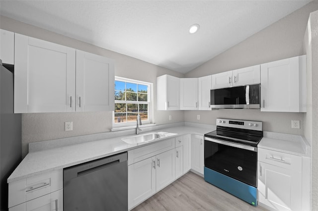 kitchen with white cabinets, sink, lofted ceiling, and stainless steel appliances