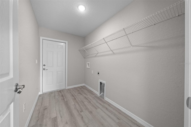 clothes washing area featuring washer hookup, hookup for an electric dryer, gas dryer hookup, a textured ceiling, and light wood-type flooring