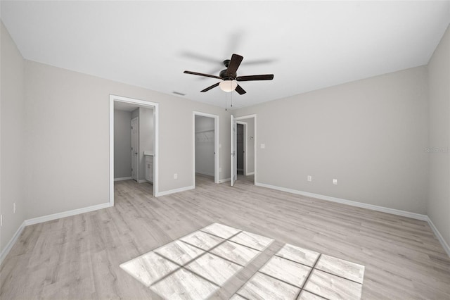 unfurnished bedroom featuring connected bathroom, ceiling fan, light hardwood / wood-style flooring, a walk in closet, and a closet