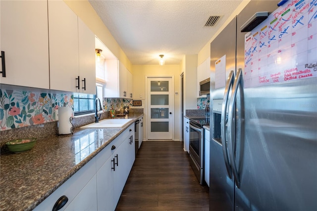 kitchen featuring stainless steel appliances, sink, dark stone countertops, white cabinets, and dark hardwood / wood-style floors