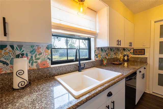 kitchen with a textured ceiling, black dishwasher, white cabinetry, and sink