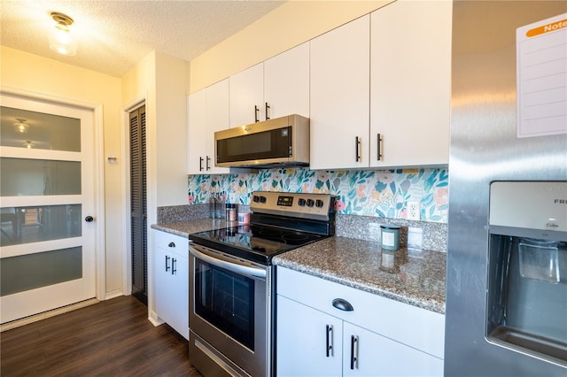 kitchen featuring dark stone counters, white cabinets, dark hardwood / wood-style floors, a textured ceiling, and appliances with stainless steel finishes