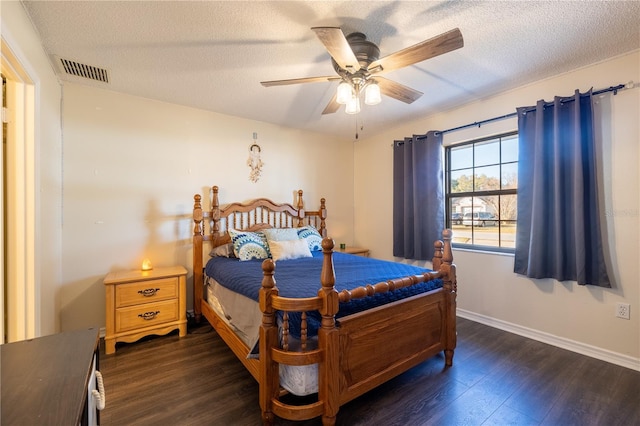 bedroom with ceiling fan, dark wood-type flooring, and a textured ceiling