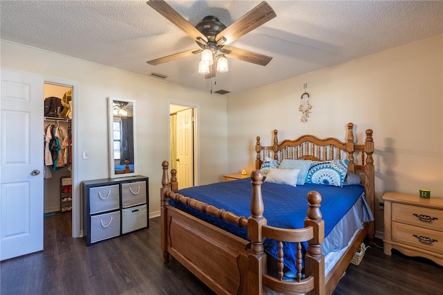 bedroom with a textured ceiling, ceiling fan, a spacious closet, dark hardwood / wood-style floors, and a closet