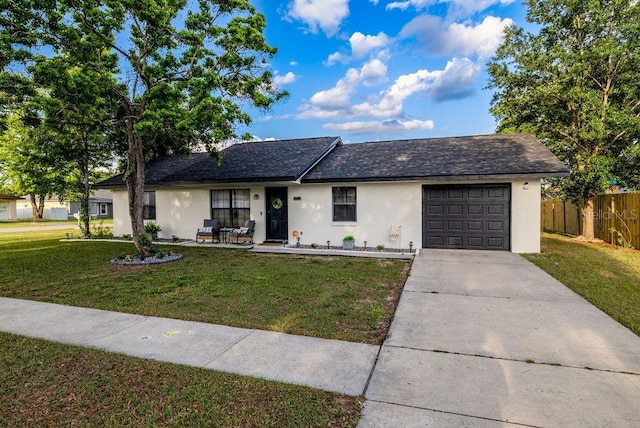 ranch-style home featuring a front yard, an attached garage, fence, stucco siding, and driveway