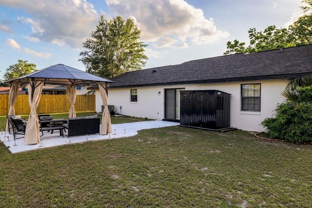 rear view of house with stucco siding, a patio area, a gazebo, fence, and a lawn