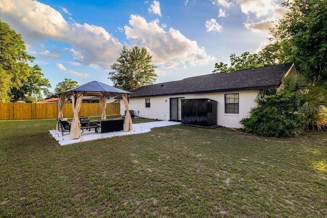 rear view of property featuring a yard, stucco siding, a patio area, fence, and a gazebo