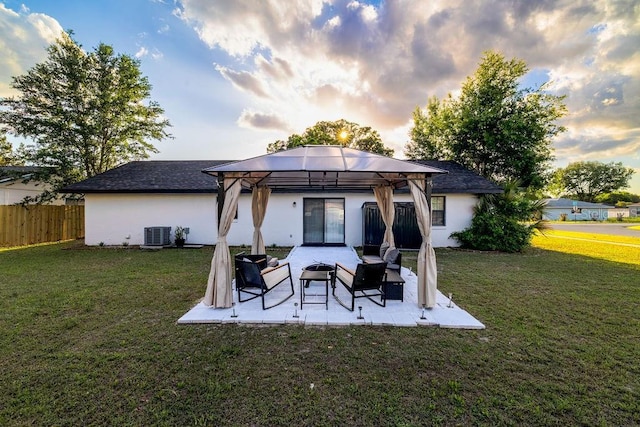rear view of property featuring stucco siding, a patio area, central AC unit, a gazebo, and fence