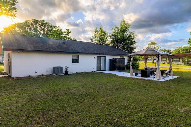 rear view of property featuring cooling unit, a yard, stucco siding, a patio, and a gazebo