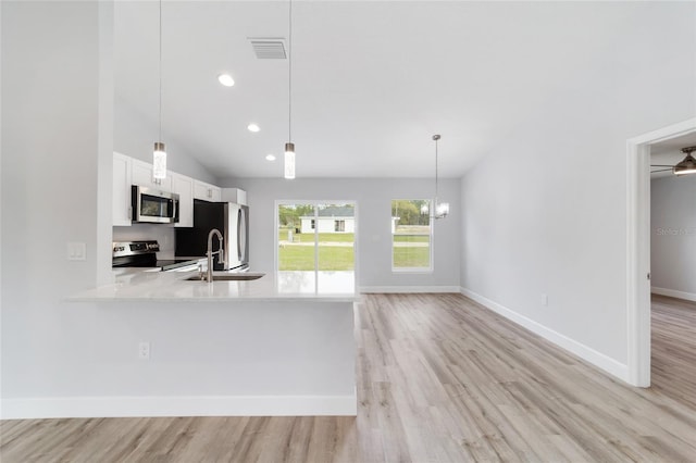 kitchen with pendant lighting, white cabinets, appliances with stainless steel finishes, light hardwood / wood-style floors, and kitchen peninsula