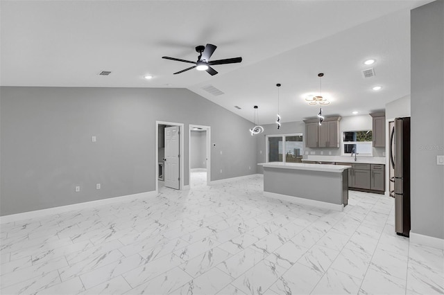 kitchen featuring ceiling fan, a center island, stainless steel fridge, lofted ceiling, and decorative light fixtures