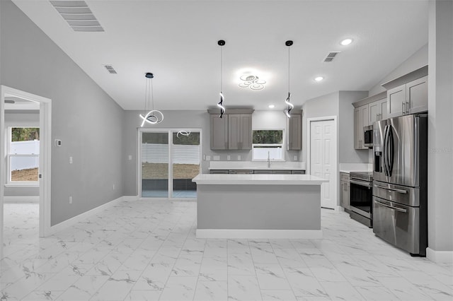 kitchen with appliances with stainless steel finishes, gray cabinetry, a kitchen island, hanging light fixtures, and lofted ceiling