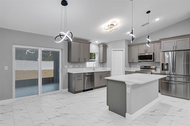 kitchen featuring lofted ceiling, sink, hanging light fixtures, appliances with stainless steel finishes, and a kitchen island