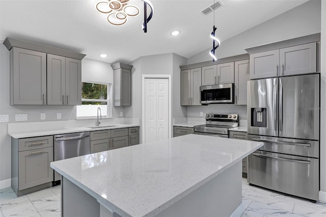 kitchen featuring pendant lighting, light stone countertops, lofted ceiling, and appliances with stainless steel finishes