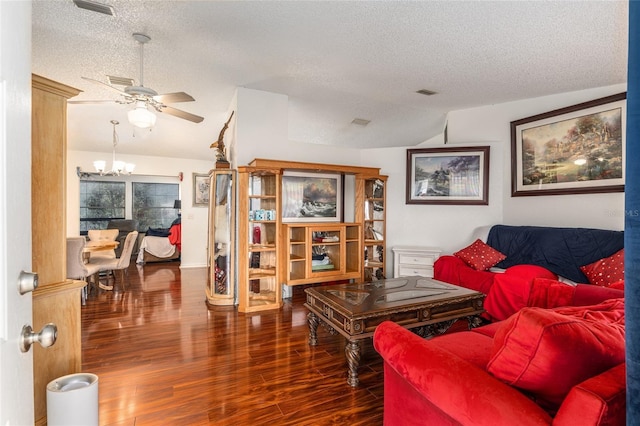 living room featuring a textured ceiling, dark wood-type flooring, lofted ceiling, and ceiling fan with notable chandelier