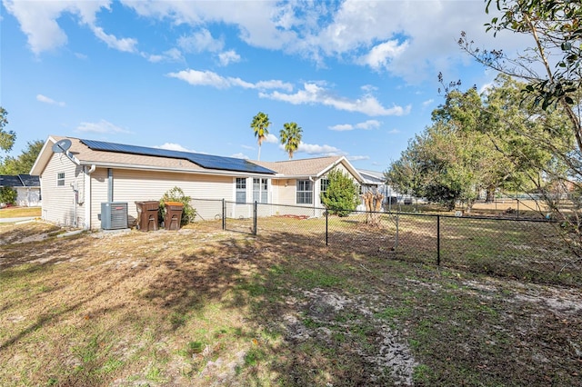 rear view of property featuring a lawn, a fenced backyard, cooling unit, and solar panels