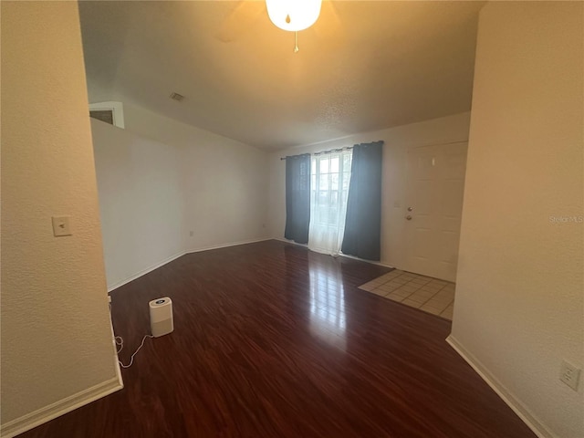 spare room with visible vents, baseboards, vaulted ceiling, and wood finished floors