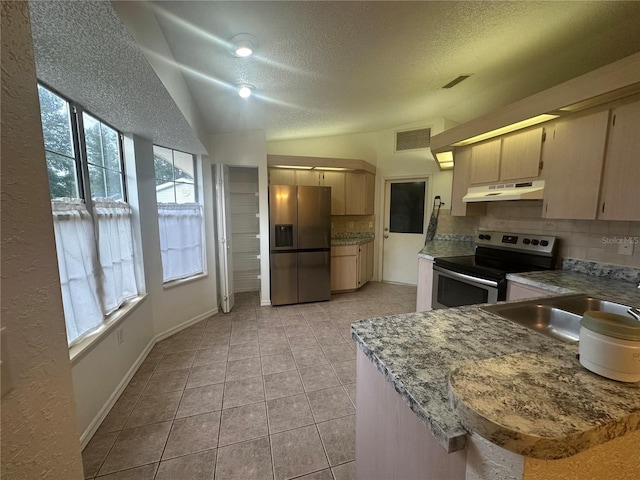 kitchen featuring tasteful backsplash, vaulted ceiling, sink, appliances with stainless steel finishes, and light tile patterned floors