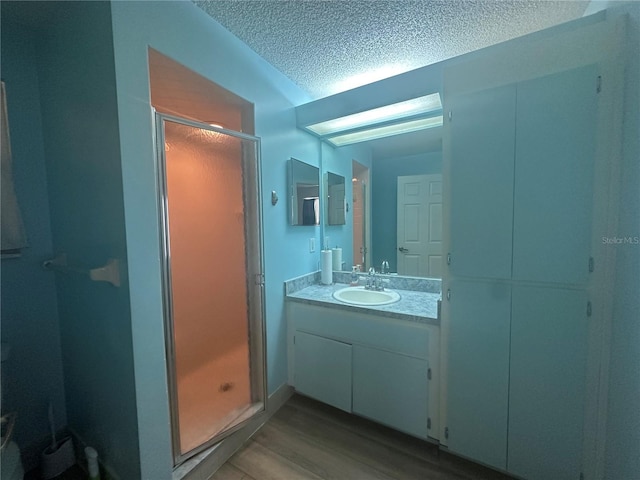 bathroom featuring a textured ceiling, a stall shower, wood finished floors, and vanity