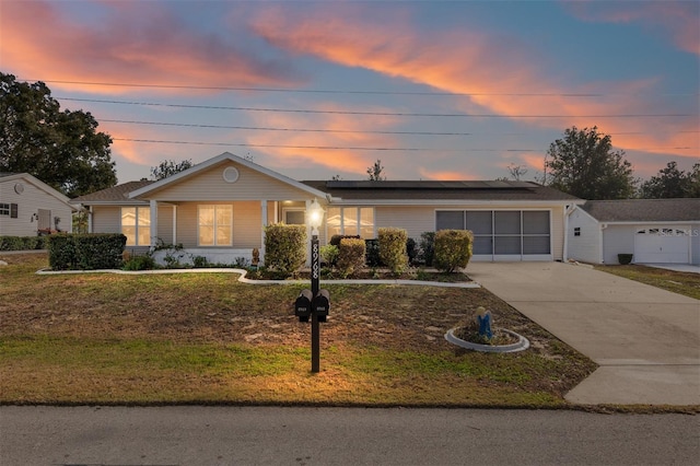 ranch-style house featuring driveway, a garage, a front lawn, and solar panels