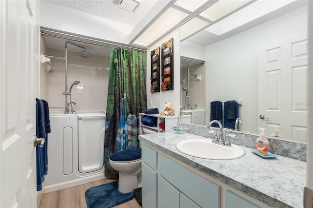 full bathroom with hardwood / wood-style floors, a textured ceiling, vanity, toilet, and shower / bath combo