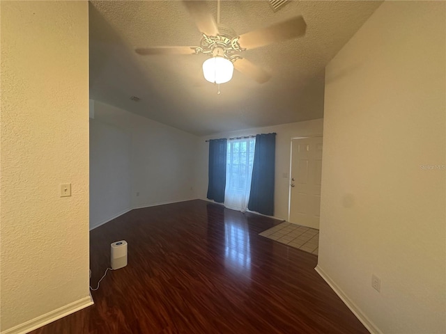 empty room featuring a textured ceiling, ceiling fan, and dark hardwood / wood-style floors