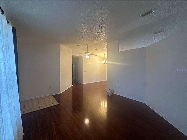 empty room with a textured ceiling, dark wood-type flooring, lofted ceiling, and ceiling fan