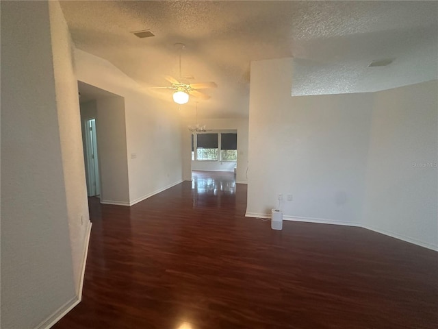 unfurnished room with a textured ceiling, vaulted ceiling, wood finished floors, and baseboards