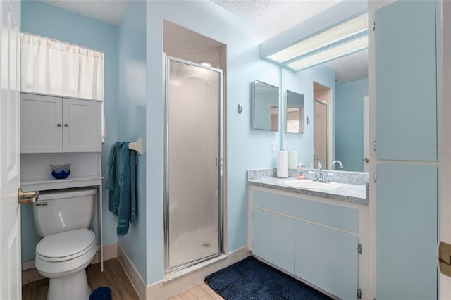 full bath with a textured ceiling, toilet, wood finished floors, vanity, and a stall shower