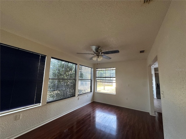 unfurnished room featuring baseboards, a textured wall, ceiling fan, wood finished floors, and a textured ceiling