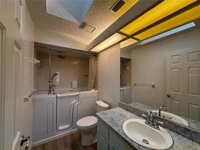 full bath featuring visible vents, toilet, a textured ceiling, vanity, and wood finished floors