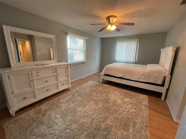 bedroom with ceiling fan, light hardwood / wood-style floors, and a textured ceiling